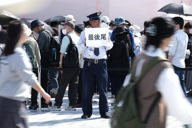 A security guard is holding a sign at the Osaka Expo site. Source: Mainichi Newspaper